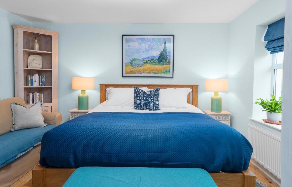 a bedroom with a large blue bed and two lamps at The Swan Inn Letton in Letton