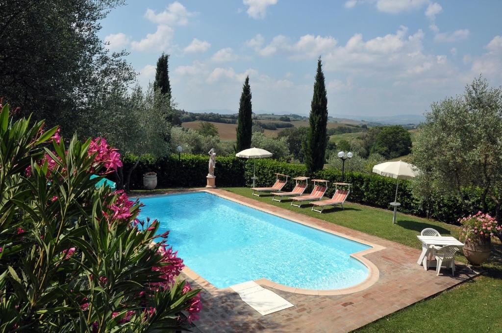 a swimming pool in a yard with chairs and umbrellas at Casale Le Capanne in Cortona