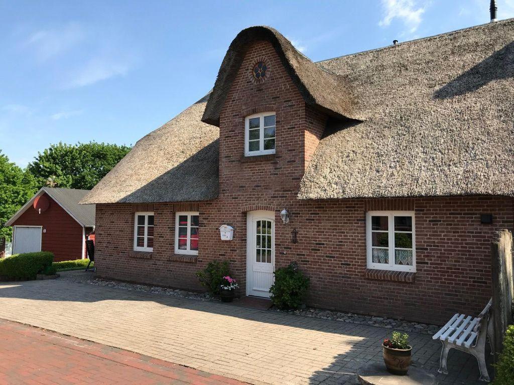 een groot bakstenen huis met een rieten dak bij Haus-Dorfstrasse in Risum-Lindholm