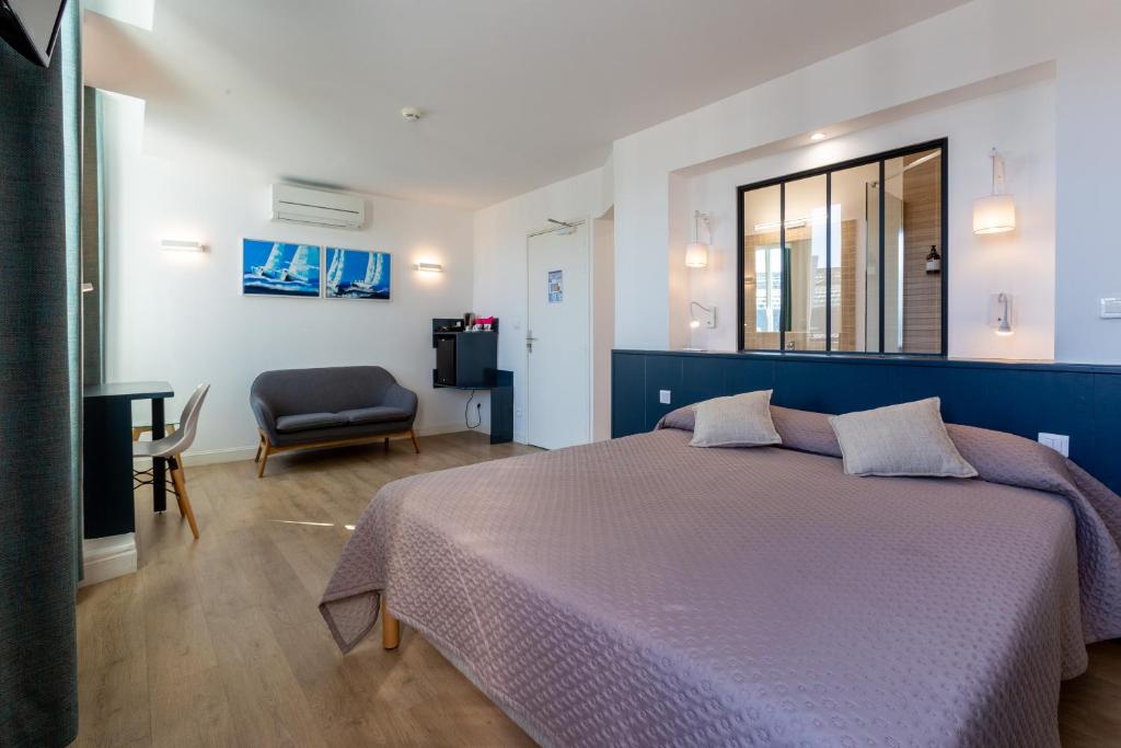 1 dormitorio con cama, silla y espejo en Citotel Le Regina Bordeaux Gare Saint-Jean en Burdeos