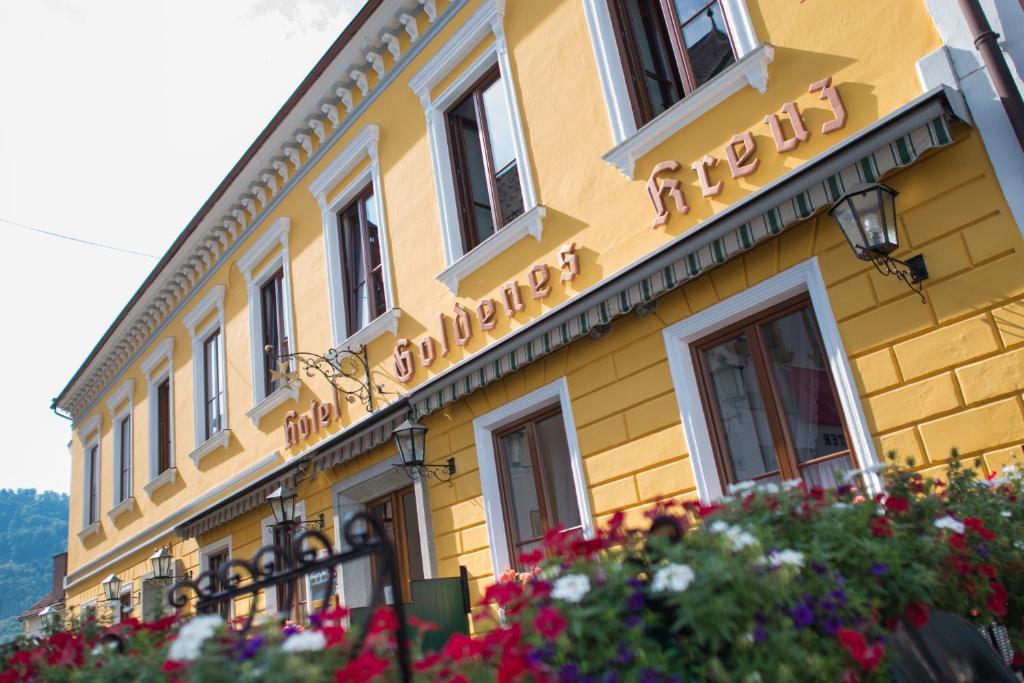 un edificio amarillo con un cartel. en Hotel-Garni Goldenes Kreuz, en Grein