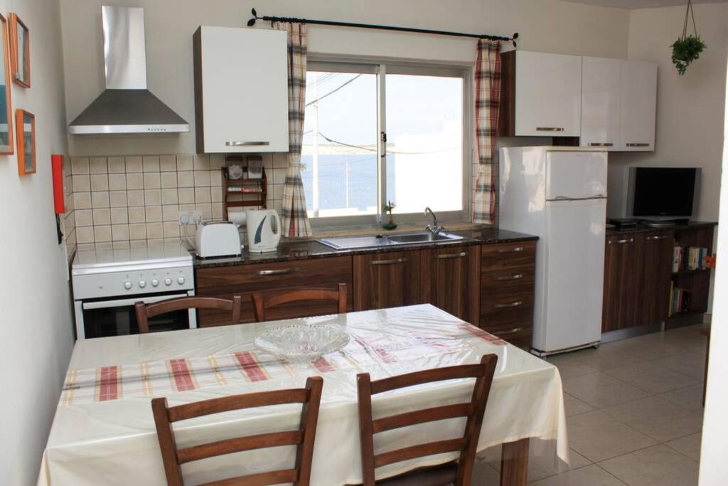 een keuken met een tafel met stoelen en een koelkast bij Fiesta Apartment Seaview in Mellieħa