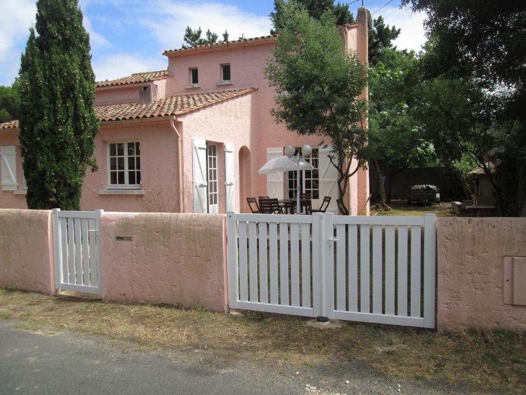 a white fence in front of a pink house at la villa rose in Saint-Trojan-les-Bains