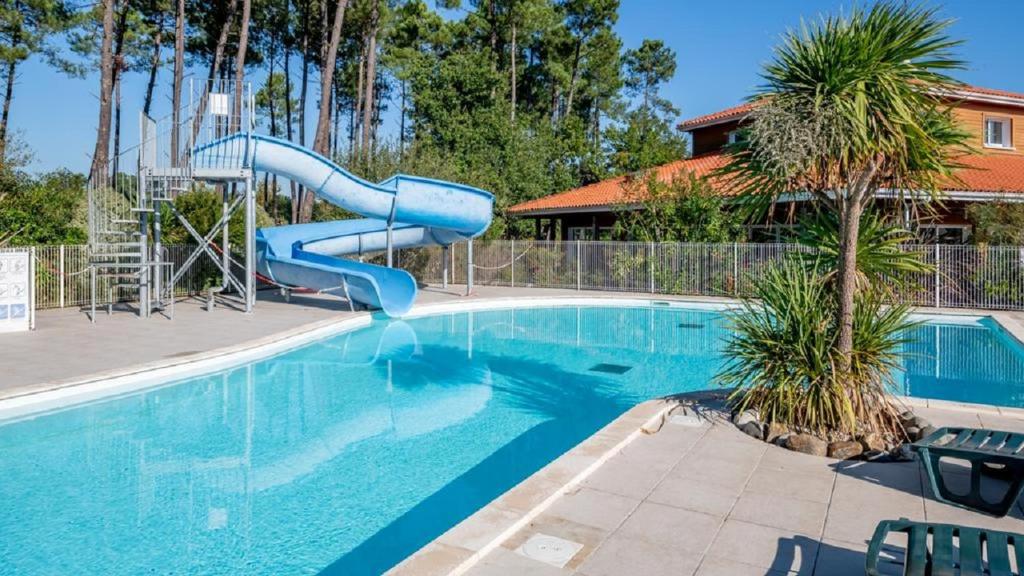 una piscina con un tobogán azul en una casa en Laouchet Le Hameau des Grands Lacs, en Parentis-en-Born