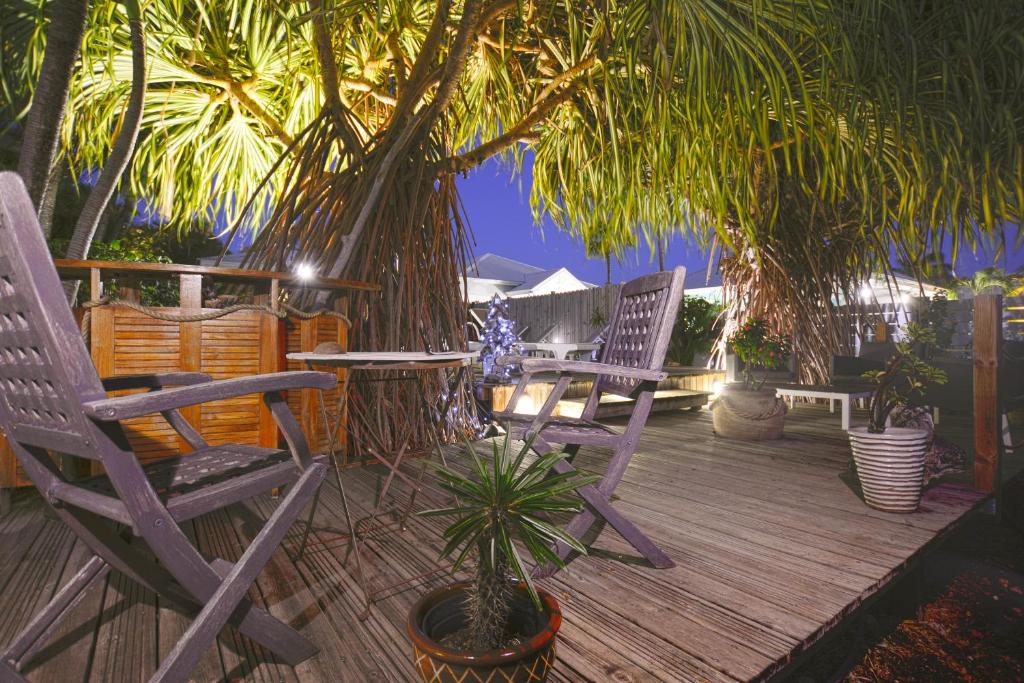 2 chaises et une table sur une terrasse avec des palmiers dans l'établissement Côté Plage, à Saint-François