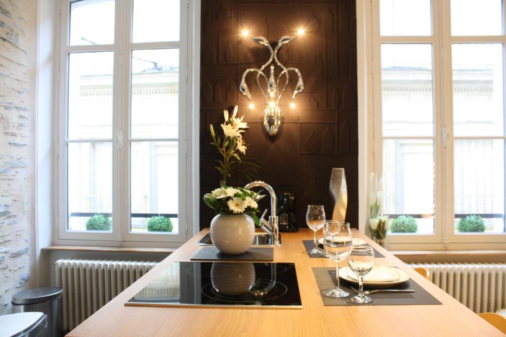 een eettafel met glazen en een vaas met bloemen bij Suit'Home Jacobins in Angers