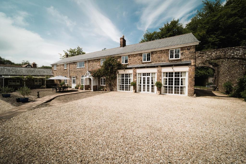 a large stone house with a large driveway at Stoodleigh Court Coach House in Tiverton