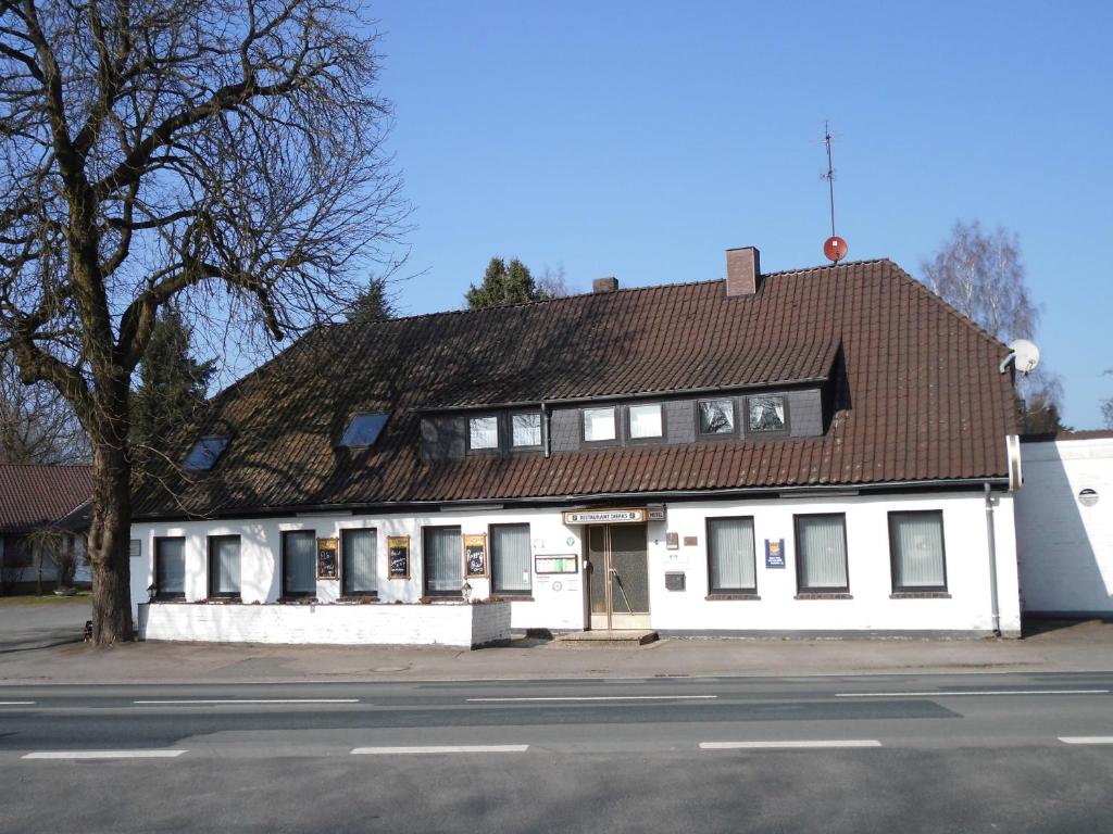 a white building with a brown roof on a street at Land gut Hotel Dierks in Repke