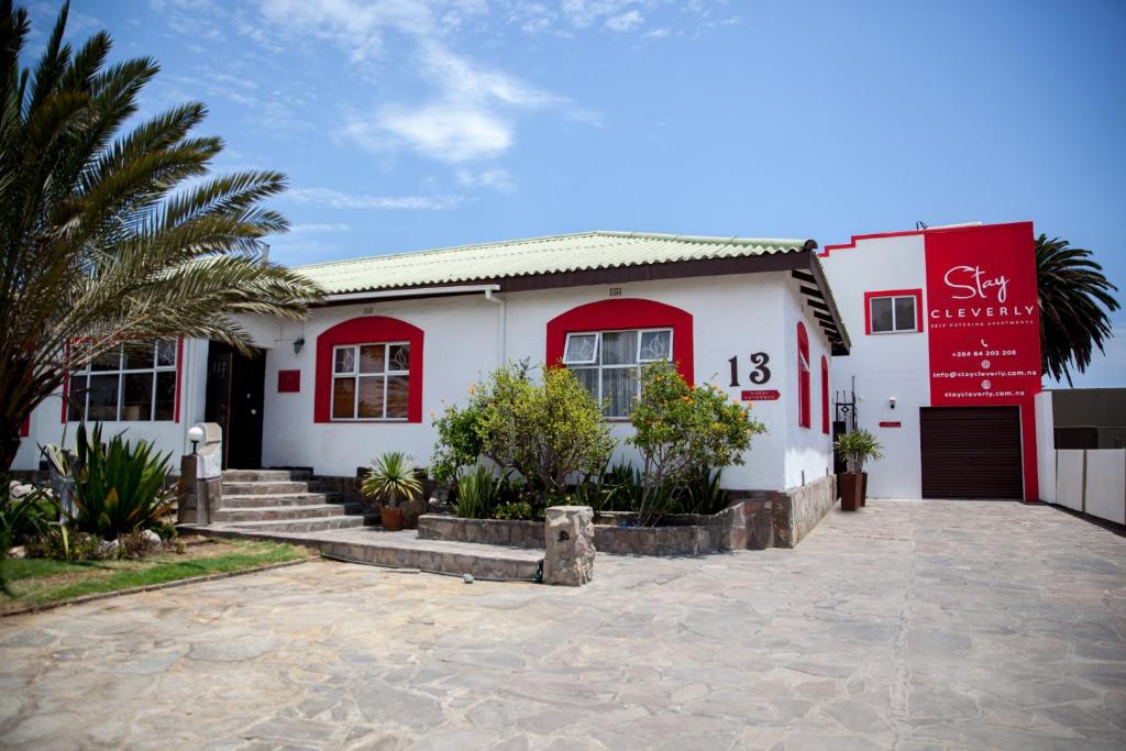 a white building with red windows and a sign on it at Stay Cleverly Self Catering Apartments in Walvis Bay