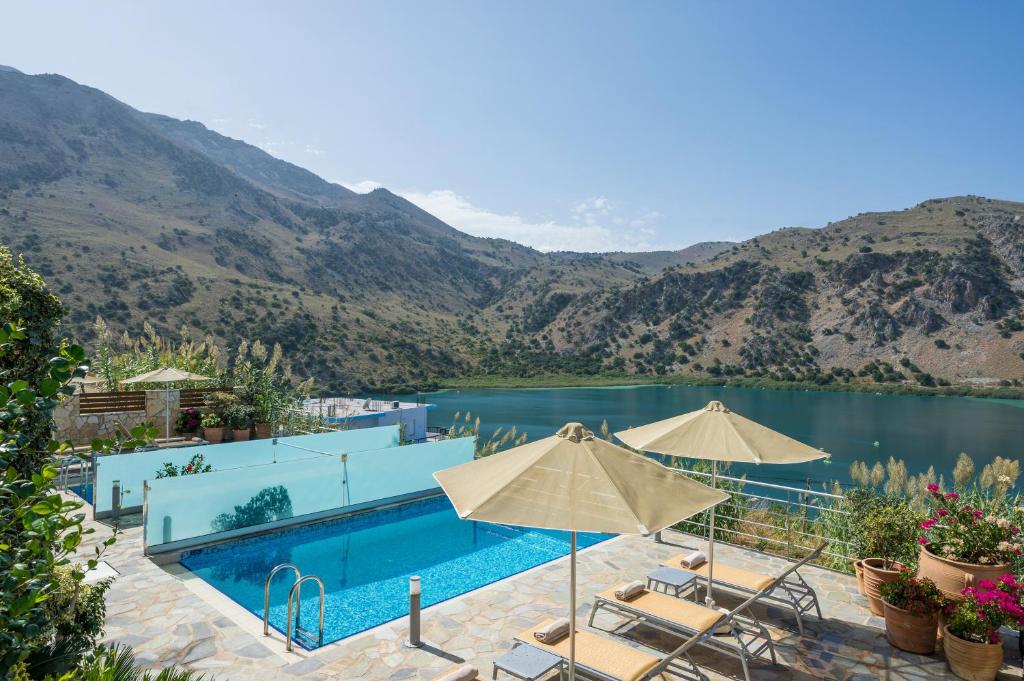 - une piscine avec des chaises et des parasols à côté d'un lac dans l'établissement Bluefairy Villas, à Kávallos
