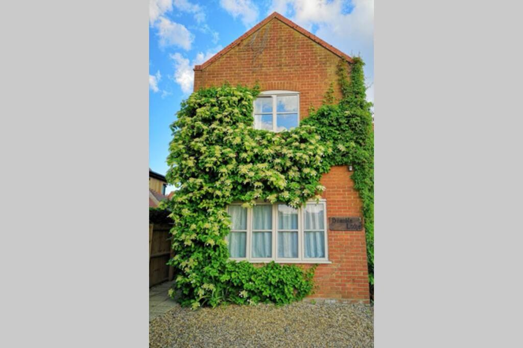 a brick house with a window covered in ivy at Blakeney Norfolk Bramble Lodge ***Self Catering*** in Blakeney