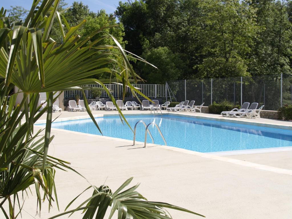 a large swimming pool with chairs and a fence at Camping La Digue in Chauzon