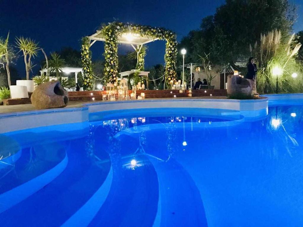 - une grande piscine bleue la nuit dans l'établissement VILLA di L ABBIU FARMHOUSE , ROOMS DESIGN & RELAX, à Sorso