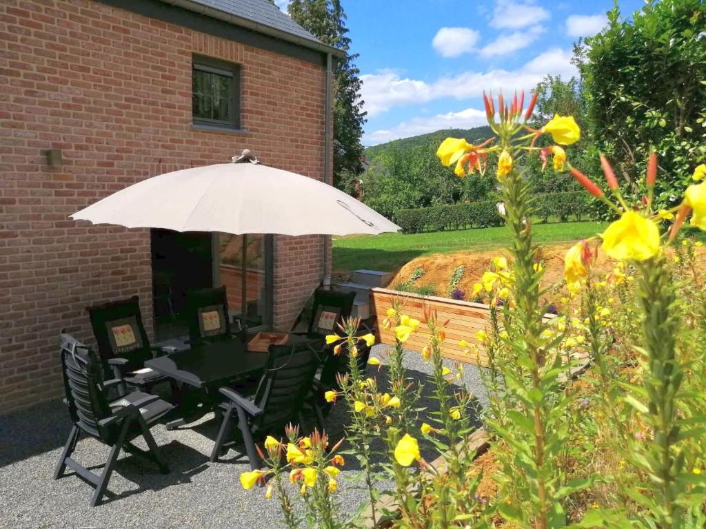une terrasse avec une table, des chaises et un parasol dans l'établissement Maison et vélos à Godinne dans la Vallée de la Meuse, à Godinne