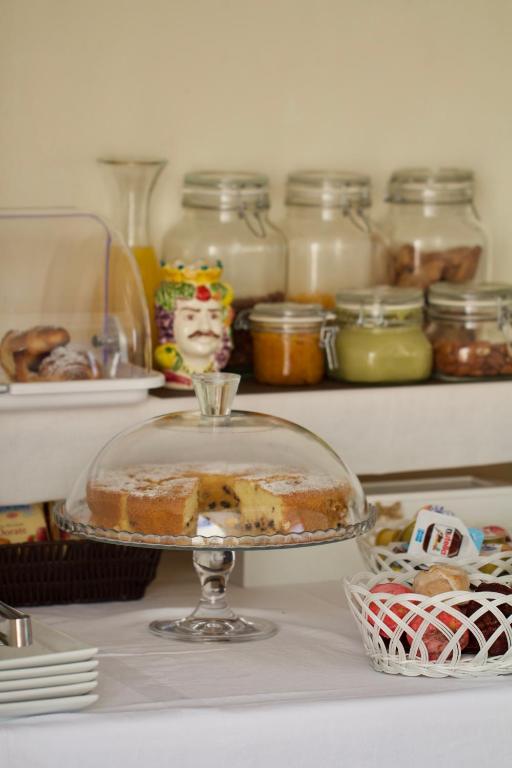 a cake in a glass dish on a counter with jars of food at La Guitgia Rooms in Lampedusa