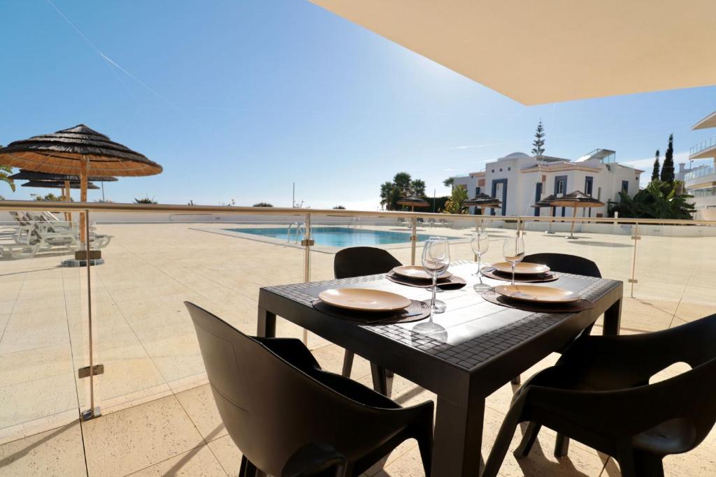 - une table noire avec des chaises et un parasol sur la terrasse dans l'établissement Olhos De Água 1BR with Pool, AC and Free Parking, à Albufeira