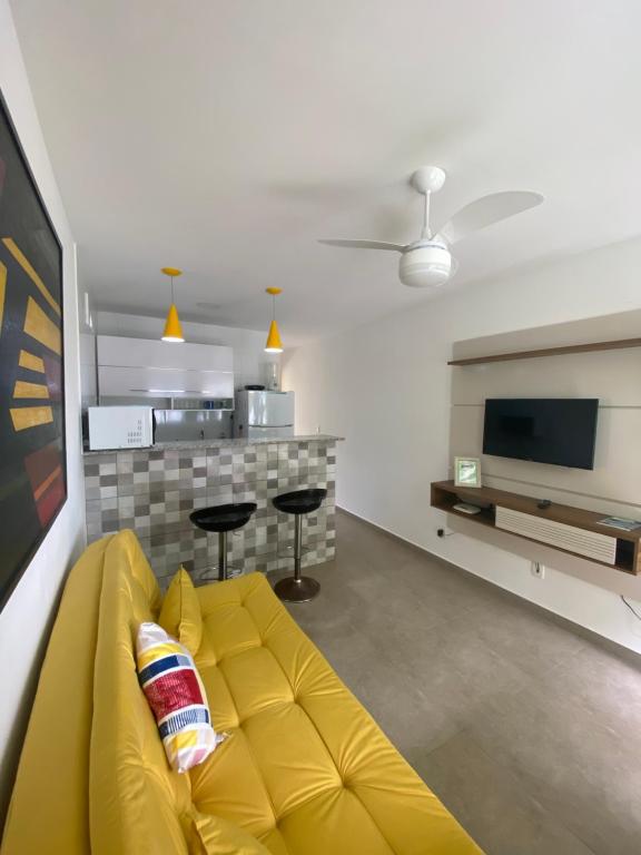 un sofá amarillo en la sala de estar con TV en Edifício Flora, en Angra dos Reis