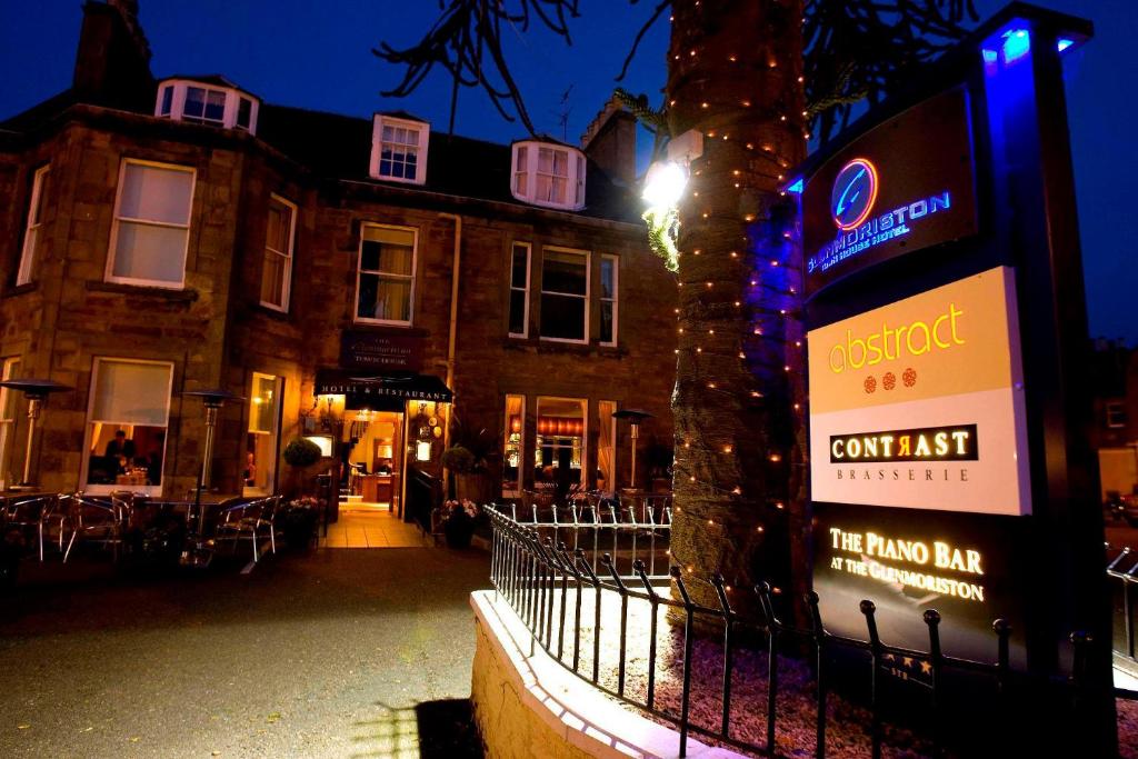 un edificio con un cartel delante de un árbol en The Glenmoriston Townhouse Hotel en Inverness
