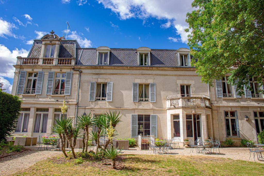 uma casa velha com um monte de árvores em frente em Hôtel Les Maréchaux em Auxerre