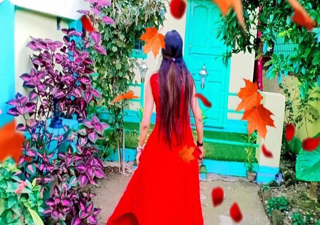 a woman in a red dress walking in front of a house at Dden Vennell BnB -Metro Access- in Kolkata