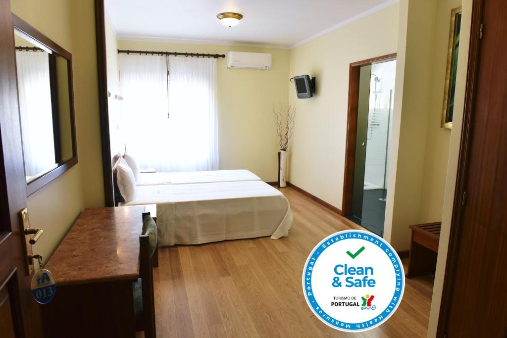 Schlafzimmer mit einem Bett, einem Tisch und einem Fenster in der Unterkunft Hotel Aeroporto in Maia