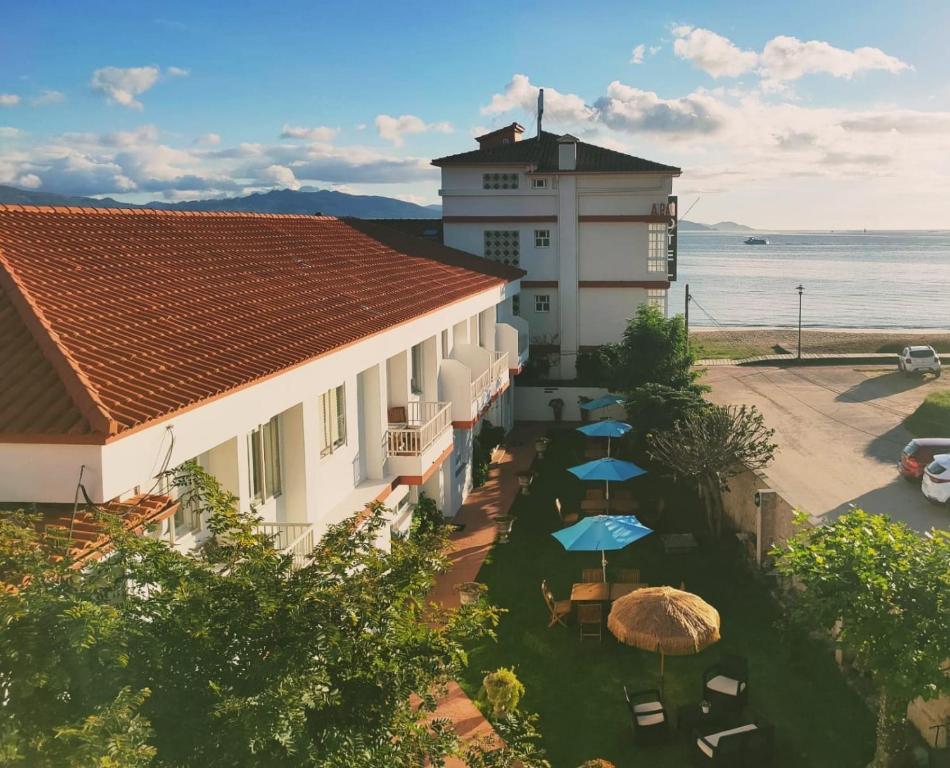 Blick auf ein Gebäude mit Sonnenschirmen und das Meer in der Unterkunft Apartamentos Rodeiramar 2A in Cangas