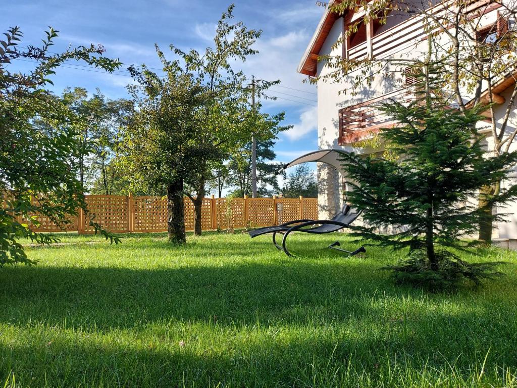 einen Hof mit grünem Gras und Bäumen und einem Zaun in der Unterkunft Modern mountain village chalet in Carpathians in Lereşti