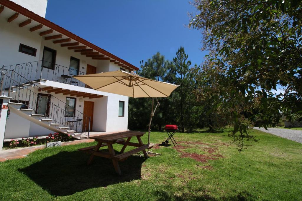 - une table de pique-nique avec un parasol en face d'une maison dans l'établissement Hacienda Soltepec Suites Campo de Golf, à Huamantla
