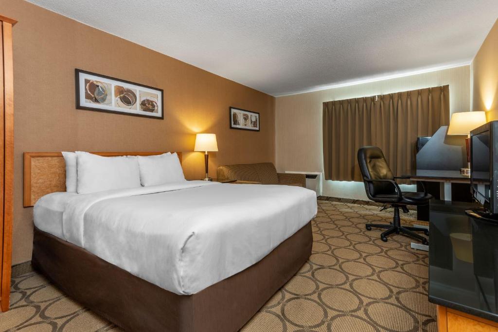 a hotel room with a bed and a desk and a television at Comfort Inn in Saguenay