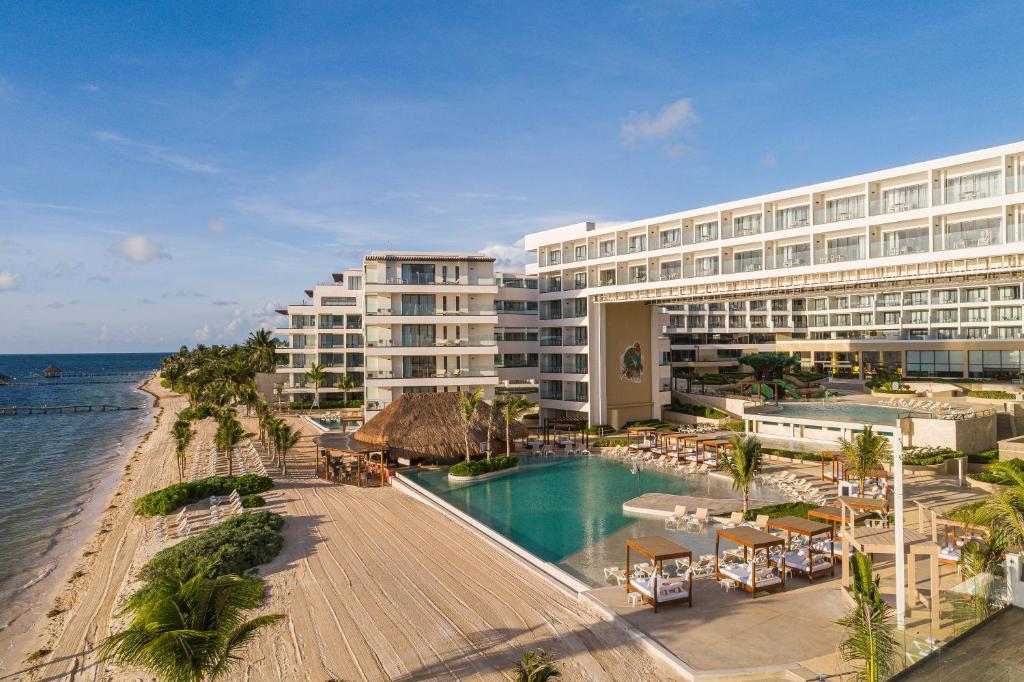 a hotel with a swimming pool next to the ocean at Sensira Resort & Spa Riviera Maya All Inclusive in Puerto Morelos