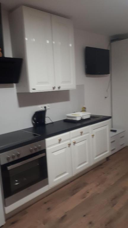 uma cozinha com armários brancos e um balcão preto em Appartement mit Terrasse 