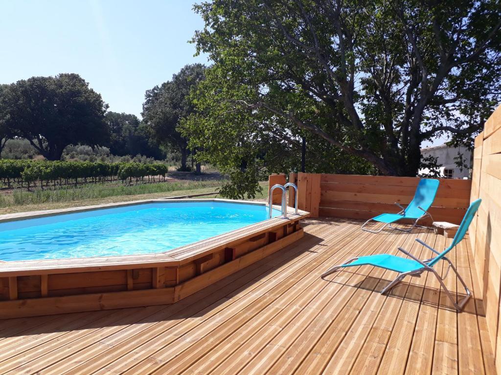 una piscina en una terraza de madera con una silla y una mesa en La Petite Maison Dans Les Vignes, en Chamaret