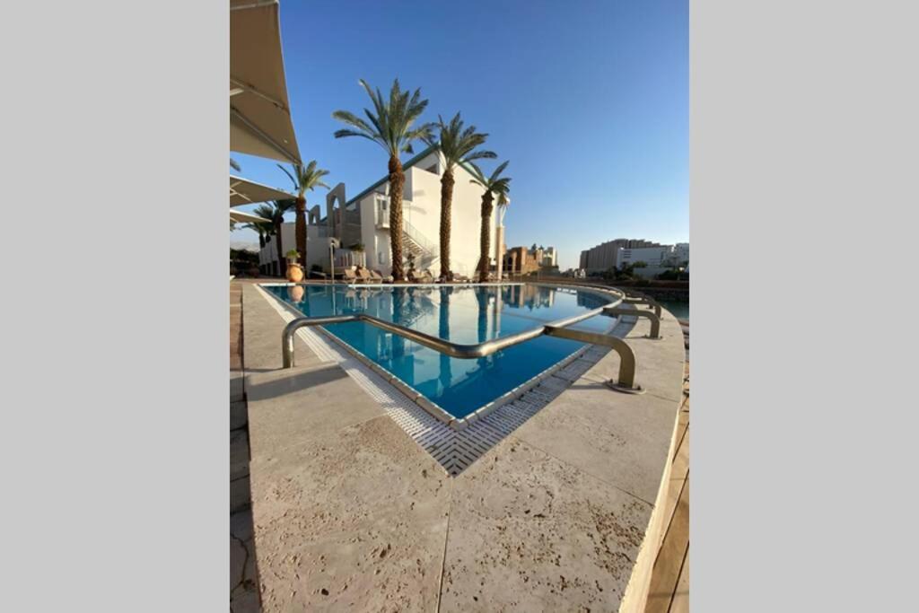einen Pool in einem Resort mit Palmen in der Unterkunft Haverim Ba’Lagouna AMAZING Duplex 3BR Front Sea in Eilat