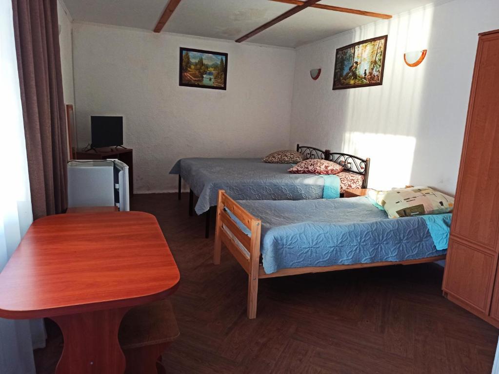 a room with two beds and a wooden table at Holiday Park Dunay in Kislitsa