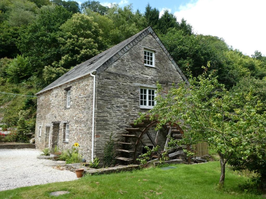 an old stone building with a large window at Jopes Mill and Lodge in Looe