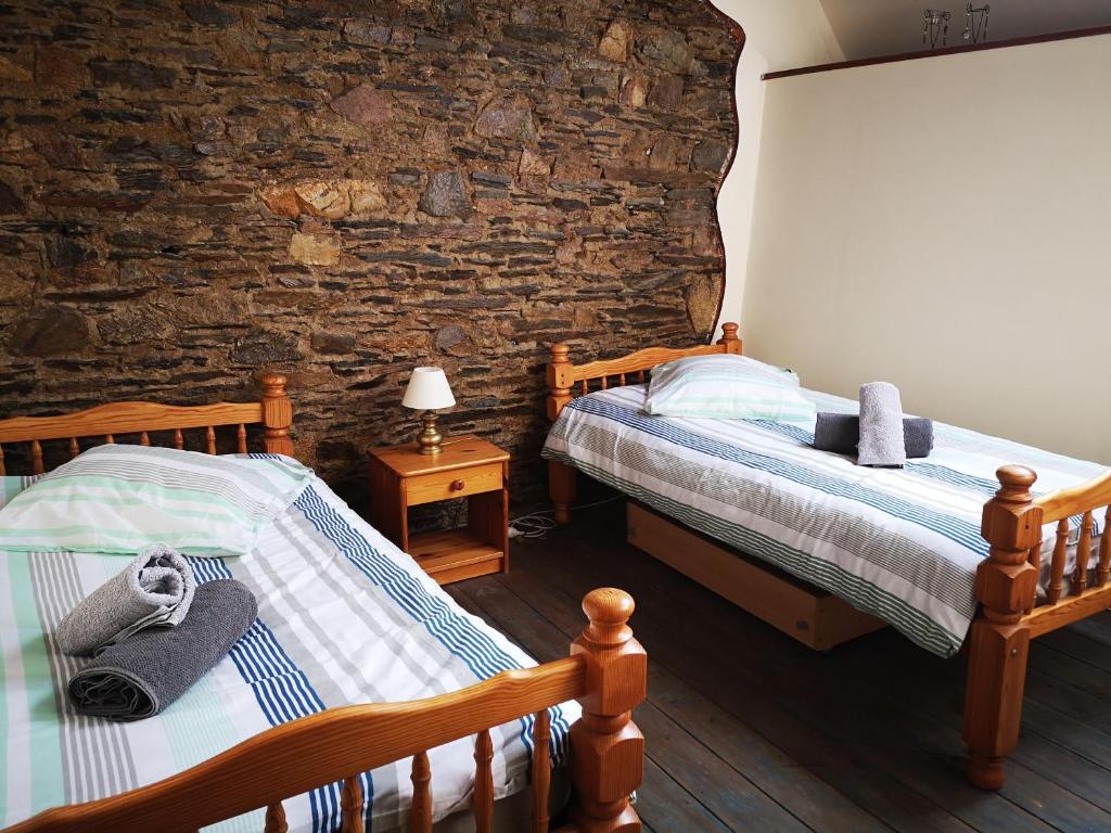 a bedroom with two beds and a stone wall at Nid douillet en Foret de Broceliande in Ploërmel