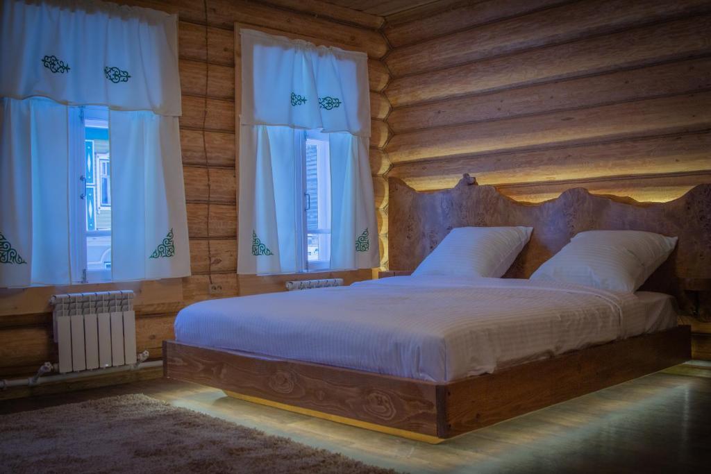 a bedroom with a large bed with wooden walls and windows at Кунак Апартаменты in Kazan