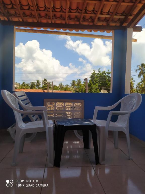 two chairs and a table in front of a window at Casa Japa Beach in Japaratinga