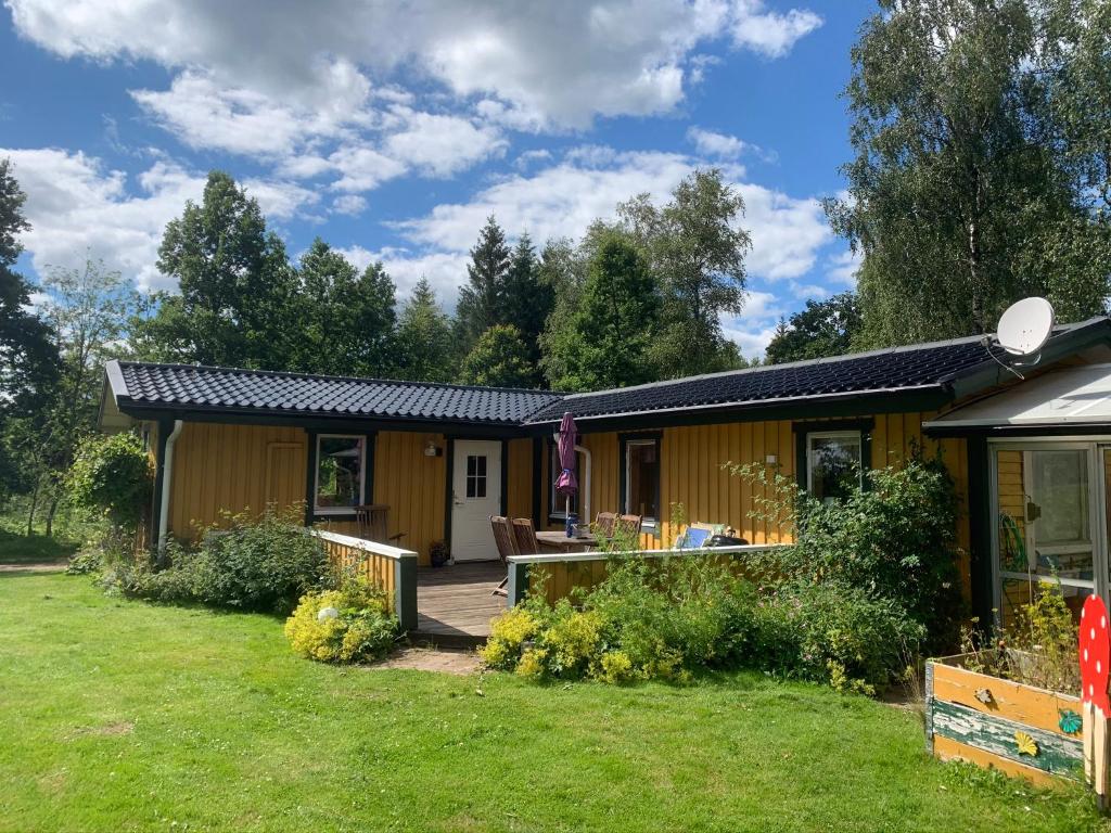 una pequeña casa amarilla con patio en Sigridstorp Åsljunga, en Orkelljunga