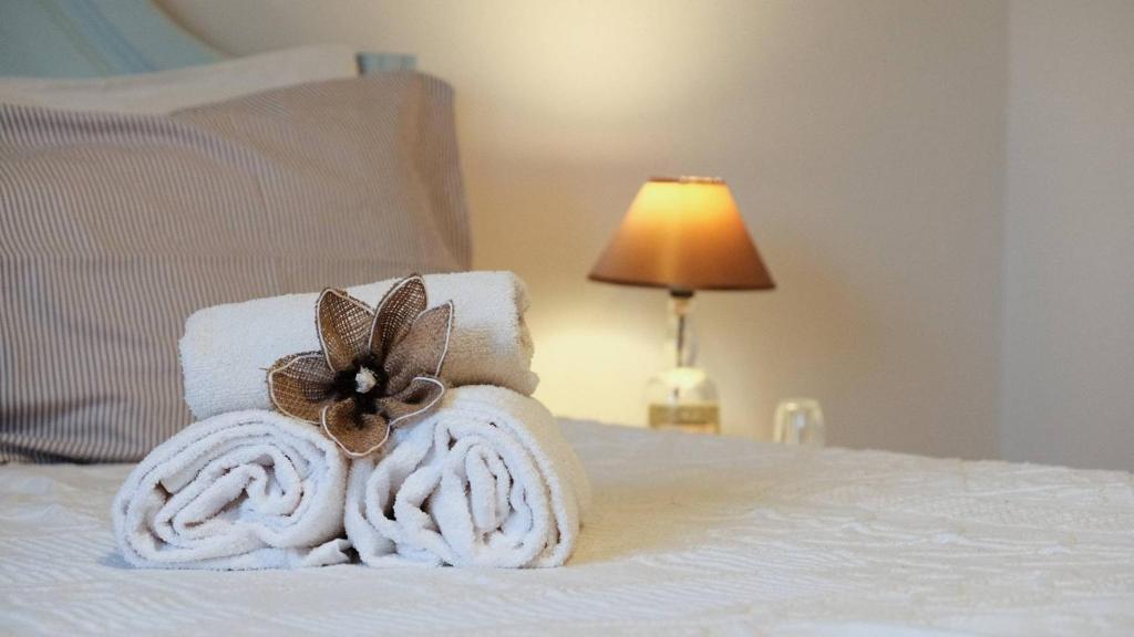 un mucchio di asciugamani su un letto con lampada di Casa das Flores a Santo Tirso