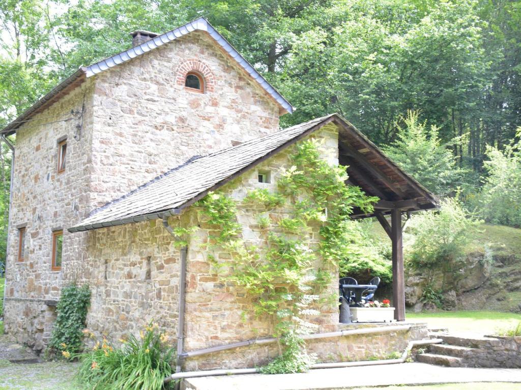 um antigo edifício de pedra com um gazebo em Cottage in the heart of the Ardennes woods em Harre