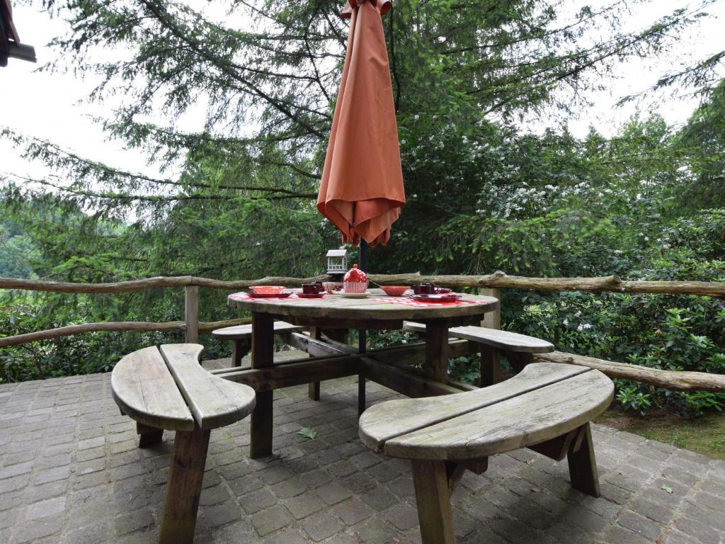 a picnic table with an umbrella and two benches at Chalet and gypsy caravan in a green and peaceful environment near Houffalize in Houffalize