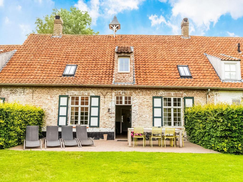 a house with a table and chairs in front of it at Historic Farmhouse in the middle of polder landscape Damme in Oedelem