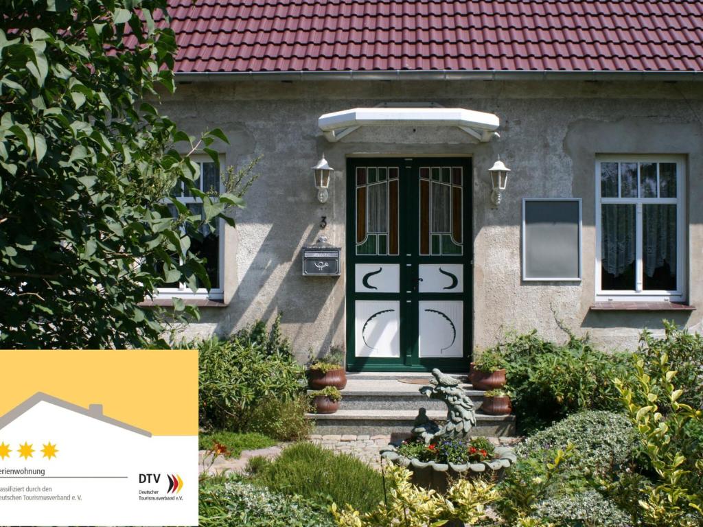 ein Haus mit grüner Tür und rotem Dach in der Unterkunft Romantische Ferienwohnung in Boldenshagen in Boldenshagen