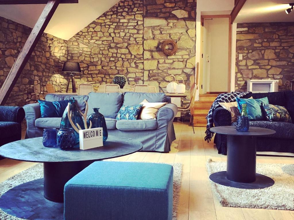 sala de estar con sofá azul y pared de piedra en Spacious Holiday Home in Vielsalm with Garden, en Vielsalm