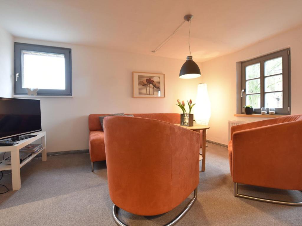 クリュツにあるStylish Apartment with Garden in Kl tz Germanyのリビングルーム(オレンジの椅子、テレビ付)