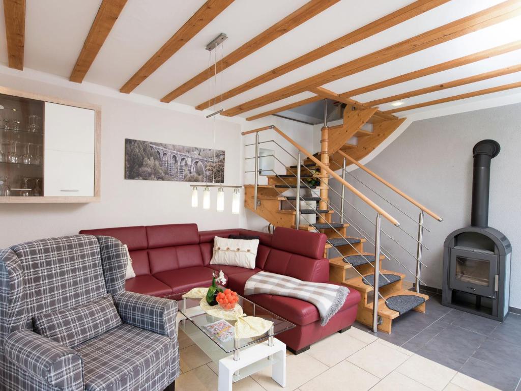 a living room with a red couch and a spiral staircase at Comfortable holiday home in Saxony with terrace in Oederan