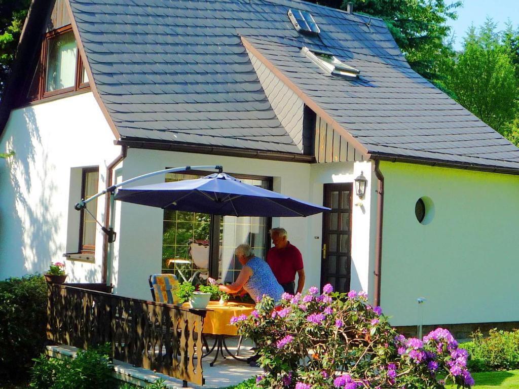 un hombre y una mujer sentados en una mesa bajo un paraguas en Holiday home in Saxony with private terrace, en Schlettau