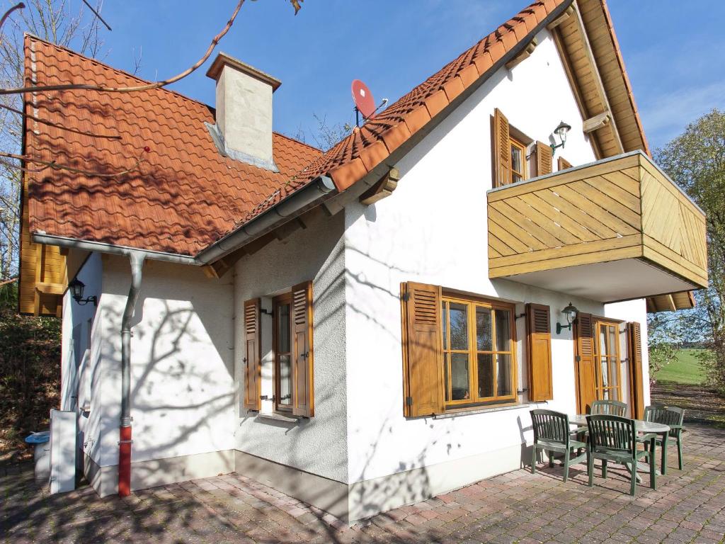 a small white house with a balcony and a table at Holiday home in the Kn llgebirge with balcony in Neuenstein