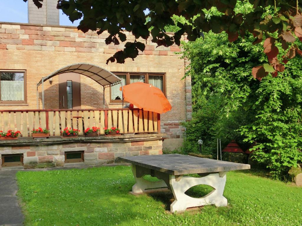 a picnic table with an orange umbrella in a yard at Attractive Holiday Home in Rotenburg with Garden in Dankerode